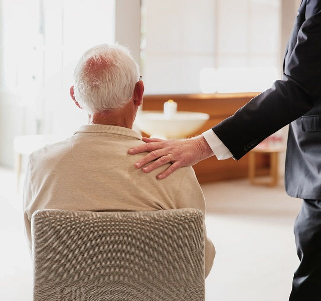 a man sitting on a chair with a person's hand on their shoulder