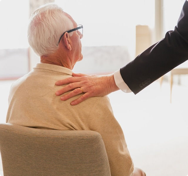 a man sitting on a chair with a person's hand on their shoulder